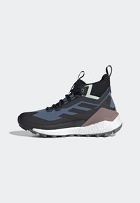 Scarpa sportiva alta nera e blu con tomaia testurizzata, intersuola bianca imbottita e suola grigia. Presenta un’etichetta per il trasporto e un logo distintivo.