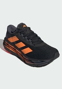 Black running shoe with orange accents, textured upper, cushioned sole, and three white stripes on the side. Features reinforced toe and laces.