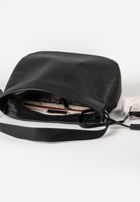 Borsa a tracolla in pelle nera con superficie texture, zip superiore e interno chiaro che presenta più tasche e una piccola borsa.
