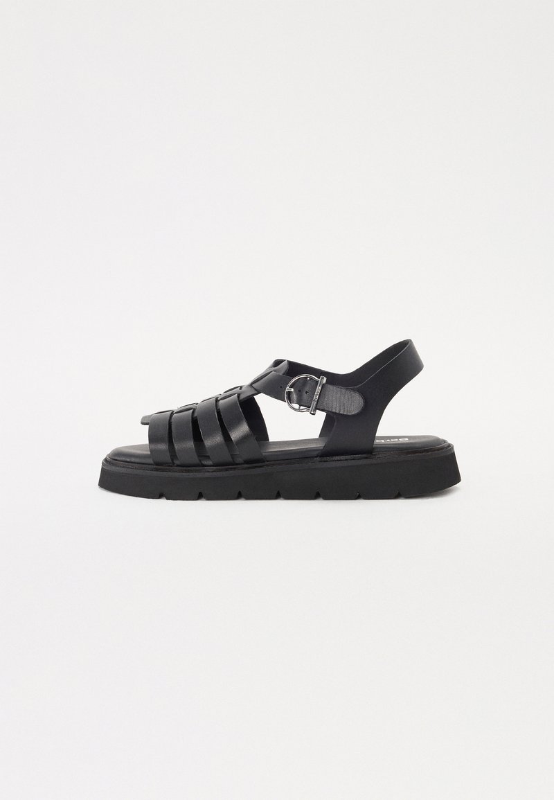 Sandale negre din piele cu un design cu curele, având o închidere cu cataramă, talpă plată și talpă exterioară din cauciuc texturat negru.