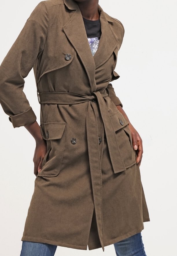 Brązowy płaszcz trench z paskiem w talii, podwójnymi guzikami z przodu oraz dwiema kieszeniami naszytymi. Wykonany z teksturowanej tkaniny o luźnym kroju.