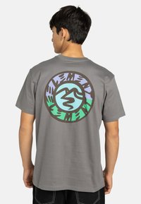 Grijze katoenen T-shirt met een kleurraf rond ontwerp op de achterkant, met blauwe, groene en bruine elementen in een ontwerp dat bergen afbeeldt.