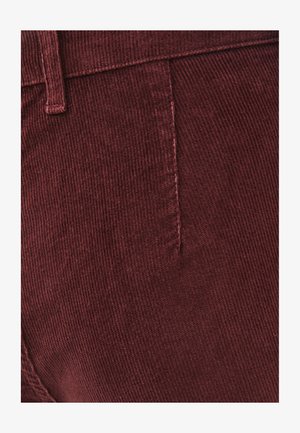 Bordeauxrode ribfluweelstof met verticale ribbelstructuur, voorzien van een zijnaad en taillebanddetail.