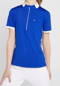 Niebieski sportowy polo z białym kołnierzykiem i akcentami. Posiada zamek błyskawiczny przy szyi oraz krótkie rękawy, wykonane z gładkiej, elastycznej tkaniny.