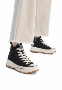 Sneaker alte nere con tomaia in cotone, lacci crema, punta in gomma e suola chunky beige con un motivo testurizzato.