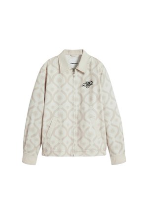Beige zip-up jacket with a pattern of light taupe shapes. Features side pockets and a black embroidered logo on the chest. Soft fabric.