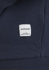 Tessuto blu navy con una trama a coste; un'etichetta bianca con la scritta "JACK&JONES" e "AUTHENTIC JEANSWEAR SINCE 1990."