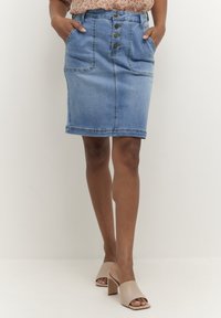 Džínová sukně světle modré barvy s pěti knoflíky vpředu, dvěma bočními kapsami a přímým střihem. Hladká textura s viditelnými detaily švů.