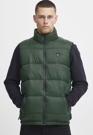 Chaleco acolchado verde con cuello alto y cremallera frontal. Cuenta con bolsillos laterales y un pequeño logotipo en el pecho. Acabado mate, diseño acolchado.