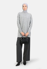 Lys grå kabelstrik sweater med lange ærmer, parret med løse mørke grå bukser. Sort håndtaske med krokodilleskinds mønster og spidse hæle.