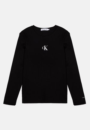 Musta pitkähihaista t-paitaa, joka on valmistettu puuvillasta ja jossa on valkoinen "cK"-logo rinnassa, pyöreä kaula-aukko ja normaali malli.