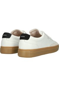 Baskets en cuir blanc avec une texture lisse, une forme arrondie, des accents de talon noirs et une semelle en caoutchouc gomme. Présentées de l'angle arrière.