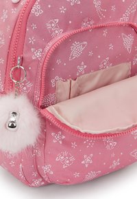 Mochila rosa con patrones florales y animales en blanco. Presenta un pompón peludo y un interior forrado en rosa con bolsillos y cierre de cremallera.
