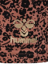 Rosa tyg med svarta blomster- och leopardmönster. Har en glittrig guldig logotyp med en bi-design och namnet "hummel" i fet stil.