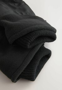 Schwarze Fleecejacke mit einer weichen Textur, mit umgeschlagenen Ärmeln und einem glatten Stoffpanel. Schlichte und funktionale Gestaltung.