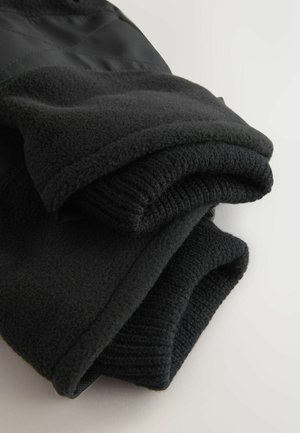 Schwarze Fleecejacke mit einer weichen Textur, mit umgeschlagenen Ärmeln und einem glatten Stoffpanel. Schlichte und funktionale Gestaltung.