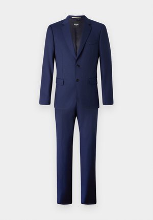 Costume bleu marine comprenant une veste ajustée à deux boutons, avec des revers en pointe, et un pantalon droit assorti. Fabriqué en tissu texturé.