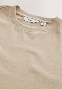 Beige sweatshirt met een geribde ronde halslijn. Zachte, gestructureerde stof met een gladde afwerking. Label zichtbaar met merk- en maatdetails.