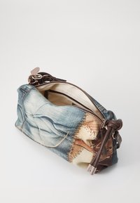 Sac en denim à finition texturée, avec des accents en cuir marron et une fermeture éclair. L'intérieur est de couleur crème avec un motif doublé.