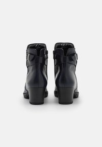 Botas de cuero navy hasta el tobillo con un tacón bloque de altura media, cremallera lateral y una correa decorativa en la parte trasera. Textura suave.