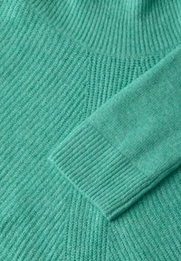Suéter verde menta con textura acanalada, que presenta un cuello tipo mock y una transición suave de la parte del cuerpo a los puños. Material de punto suave.
