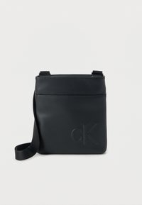 Μαύρη δερμάτινη τσάντα χιαστί με ανάγλυφο λογότυπο «cK», λεία υφή, ρυθμιζόμενο λουράκι και μπροστινή τσέπη για επιπλέον αποθήκευση.