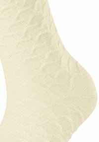 Chaussette crème jusqu'au genou avec un motif en losanges, tricot texturé et finition lisse. Comprend un renfort à la pointe et au talon pour une durabilité accrue.