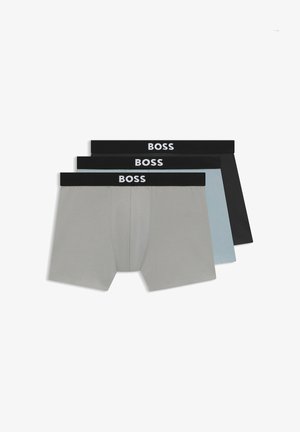 Trzy pary męskich bokserek: szare, jasnoniebieskie i czarne. Każde mają czarną gumkę z napisem "BOSS" w białych literach.