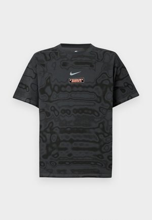 Camiseta preta com padrão texturizado, apresentando um pequeno logótipo da Nike em azul claro e uma etiqueta de logótipo retangular em cores contrastantes.