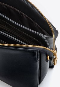 Borsa in pelle nera con zip dorata, dotata di molteplici scomparti e finitura testurizzata. Include tasche interne con zip e tasche a civetta.
