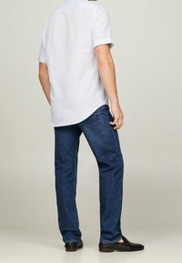 Vaaleansininen lyhythihainen paita yhdistetty tummansinisiin farkkuihin. Paidassa on suora helma; farkut ovat suoralahkeiset, joissa hienovaraiset ompelut.