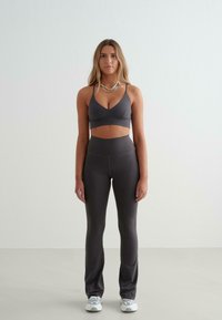 Grijze sportbeha en bijpassende hoogwaardig doorgestikte legging in een gladde stof, met een minimalistisch ontwerp, dunne bandjes en een lage halslijn.