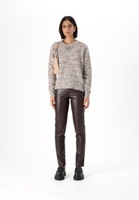 Pull en tricot dans des tons beige et marron, associé à un pantalon slim en simili cuir marron et des mocassins noirs à plateforme. Sac à bandoulière simple inclus.
