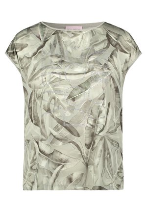 Blouse à manches courtes avec motif de feuilles tropicales vertes et grises, encolure ronde, et détail subtil de texte en strass sur le devant.