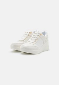 Weiße Sneakers mit strukturierter Oberfläche, Schnürung an der Vorderseite, goldenen Ösen und einer dicken Plattform-Sohle. Verfügt über ein seitliches Paneeldesign und glatte Akzente.