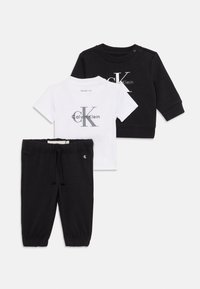 Sweatshirt noir à manches longues, t-shirt blanc à manches courtes avec le logo "Calvin Klein", et pantalon noir à cordon de serrage pour bébés.