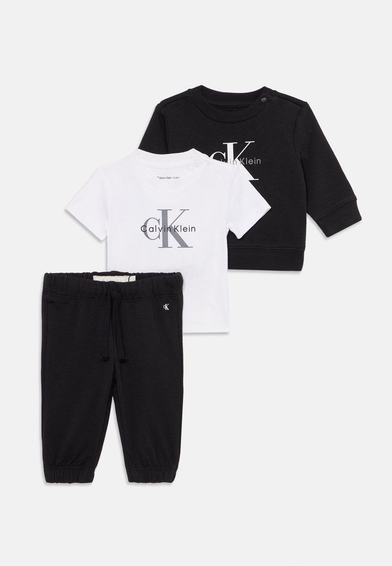 Sweatshirt noir à manches longues, t-shirt blanc à manches courtes avec le logo "Calvin Klein", et pantalon noir à cordon de serrage pour bébés.