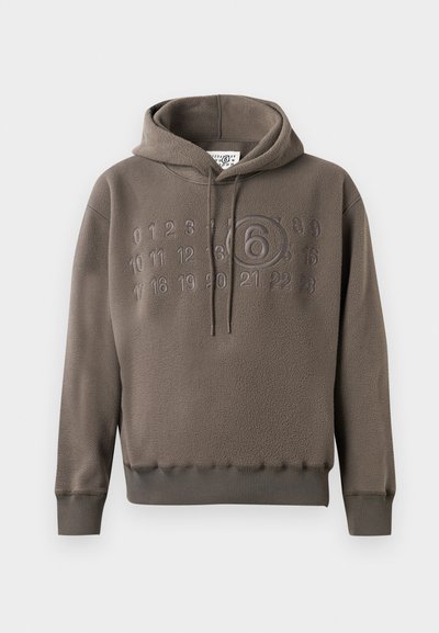 Καφέ φλις φούτερ με ανάγλυφους αριθμούς από το 0 έως το 23 στο στήθος, με έναν μεγενθυμένο κυκλωμένο αριθμό 6 στο κέντρο.