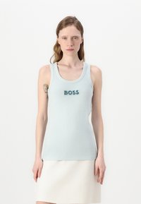 Svetlo modra brezrokavna majica z ribasto strukturo in zaobljenim ovratnikom. Ponuja besedo "BOSS" v temno modri okrasni barvi.