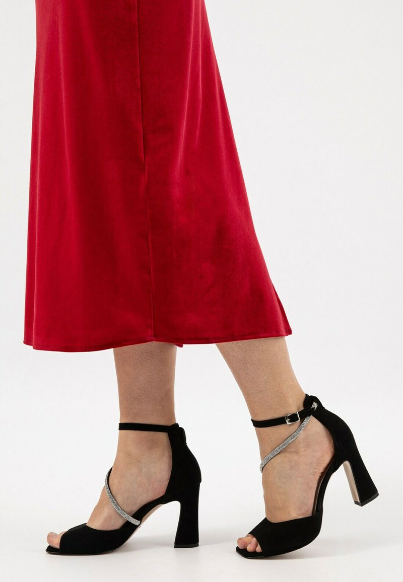 Sandali con tacco alto in suede nero, con una fascia testurizzata e dettagli in argento, dotati di un design open-toe e cinturino alla caviglia.