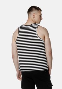 Czarnobiała bluzka na ramiączkach w paski o zaokrąglonym dekolcie, bez rękawów i luźnym kroju, wykonana z lekkiego materiału dla wygody.