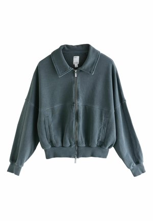 Dunkelgrüne Bomberjacke mit Reißverschluss, Kragen, oversized Schnitt, geripptem Saum und seitlichen Taschen. Hergestellt aus weichem, strukturiertem Stoff.