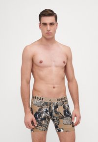 Beige színű férfi boxer short, fekete és arany bajnoki gyűrűk mintájával. Rugalmas derékpánt "JORDAN" márkázással. Pamut keverék anyag.