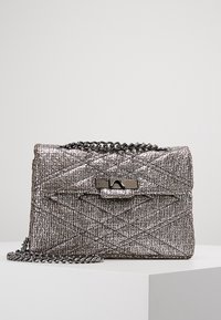 Bolso de mano metálico plateado con textura acolchada, que presenta un cierre de solapa y una correa de cadena. La superficie tiene un brillo sutil y un herraje elegante.