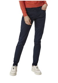 Granatowe, slim-fit spodnie wykonane z lekkiego materiału, z bocznymi kieszeniami i gładką teksturą, w połączeniu z jasnymi trampkami.