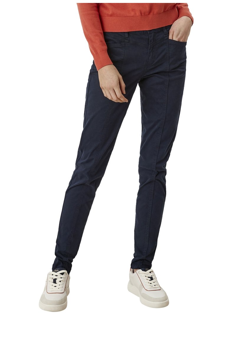 Granatowe, slim-fit spodnie wykonane z lekkiego materiału, z bocznymi kieszeniami i gładką teksturą, w połączeniu z jasnymi trampkami.