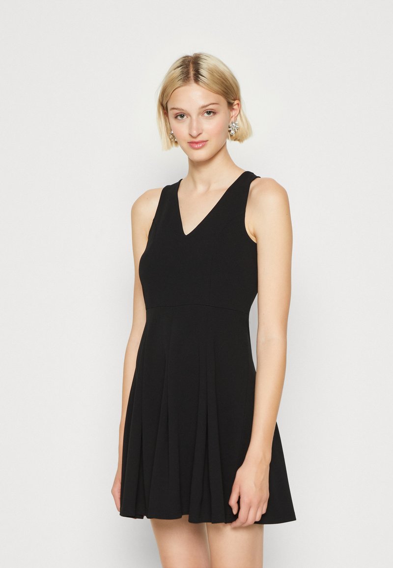Une robe noire sans manches avec un décolleté en V, un corsage ajusté et une jupe plissée évasée, fabriquée à partir d'un tissu doux au toucher lisse.