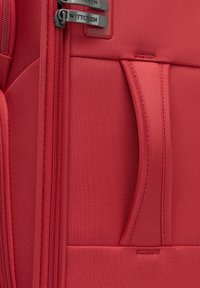 Czerwona torba podróżna z teksturowanym materiałem, podwójnymi zamkami i przednią kieszenią. Logo marki "WITTCHEN" widoczne na uchwytach zamków.