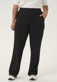 Pantalons larges noirs en tissu doux avec une texture lisse. Dotés de poches latérales et d'une taille haute pour un confort optimal.