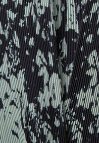 Svart och ljusgrön mönstrad tyg med vertikala ribbor. Designen har abstrakta former och en texturerad yta.